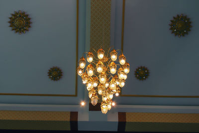 Low angle view of illuminated chandelier hanging from ceiling