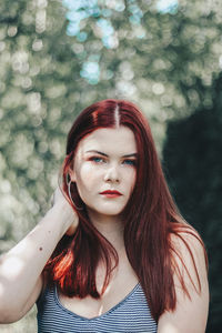 Portrait of beautiful woman standing against tree