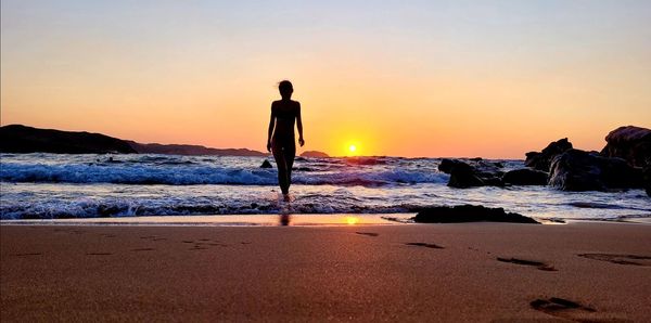 Silhouette man standing on beach during sunset