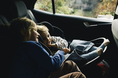 Sisters talking to each other sitting at back seat in car