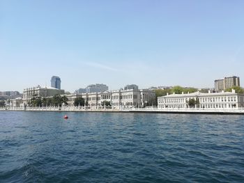 Sea by buildings against clear blue sky