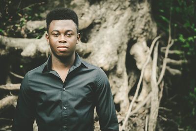 Portrait of man standing by tree trunk