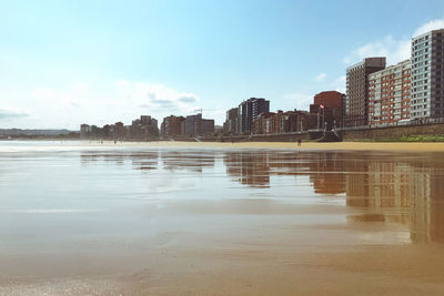 Scenic view of lake by buildings against sky in city