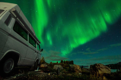 Vehicle on field against aurora polaris