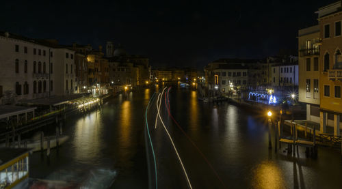 Canal amidst illuminated city against sky at night