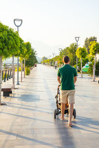 Rear view of man riding bicycle on footpath