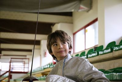 Cute boy looking away while practicing fencing