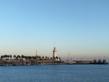 View of lighthouse by buildings against clear sky