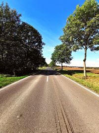 Road amidst trees in city against sky