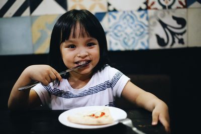 Portrait of little girl eating in restaurant