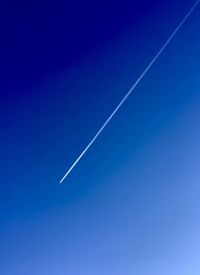 Low angle view of vapor trail against clear blue sky