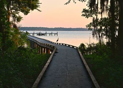 Pier over lake against sky during sunset