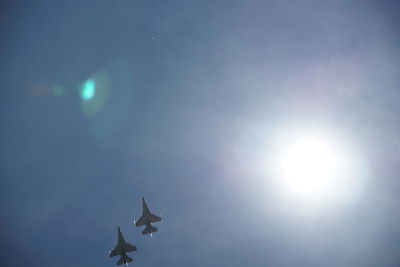 Low angle view of sun shining through clouds