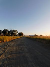 Road amidst trees against clear sky