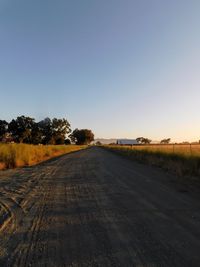 Road amidst trees against clear sky