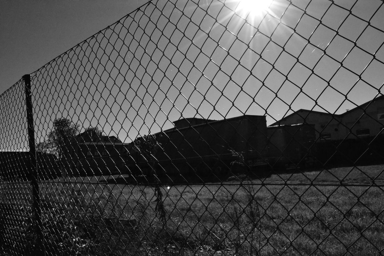 fence, sunlight, sky, chainlink fence, protection, pattern, sun, metal, built structure, architecture, shadow, safety, silhouette, lens flare, railing, window, sunbeam, no people, indoors, day