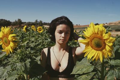 Portrait of young woman in bikini standing on field