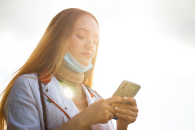 Portrait of young woman using mobile phone against white background