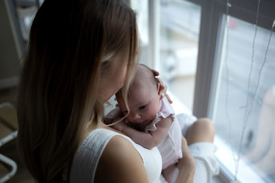 Side view of young woman looking through window