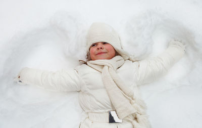 Full length of cute baby girl lying in snow