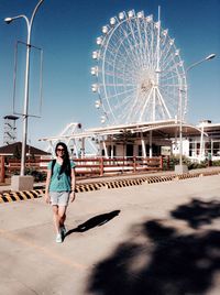 Full length portrait of woman standing at amusement park against sky