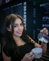 Portrait of a smiling young woman drinking glass