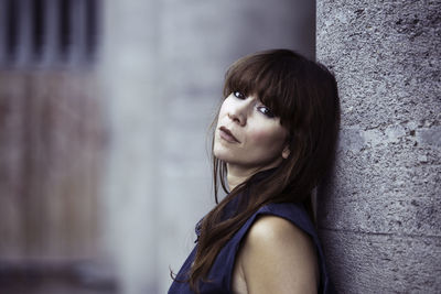 Portrait of young woman standing against blurred background