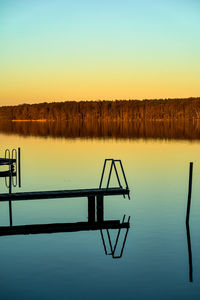 Wooden post in lake against sky during sunset