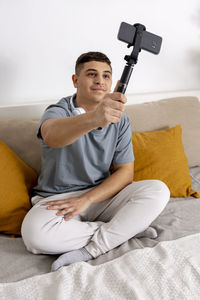 Young man, blogger recording lifestyle blog, talking to camera of smartphone on tripod. influencer