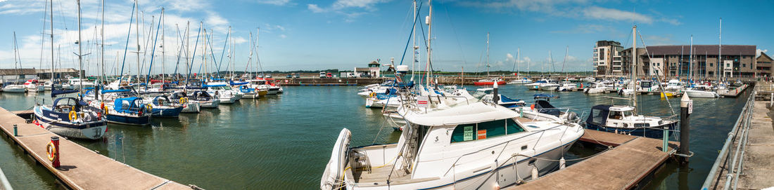 Boats moored at harbor against sky