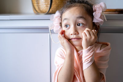 A little girl is standing in a beautiful dress with hair accessories. pretend play at home.