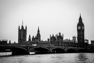 Westminster bridge and big ben by thames river against sky in city