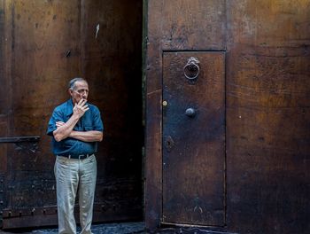 Full length portrait of man standing on wooden door