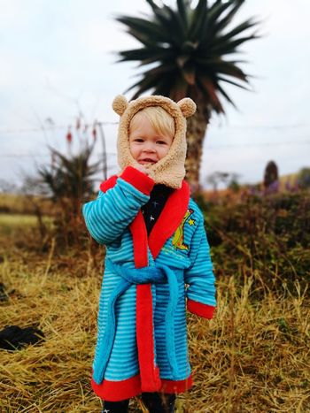 Portrait of boy wearing warm clothing on field against sky
