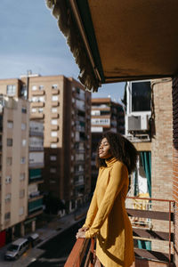 Young woman standing with eyes closed at balcony