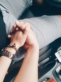 Cropped image of couple with holding hands in car