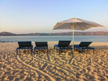 Deck chairs on beach against clear sky