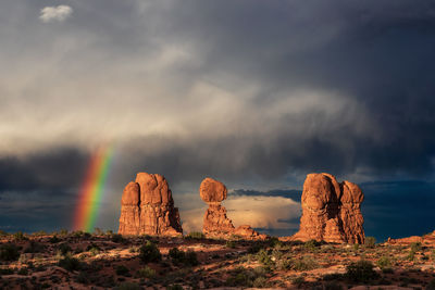 Vivid rainbow and stormy sky over balanced rock in arches national park, utah