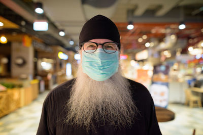 Portrait of man wearing mask standing at shopping mall