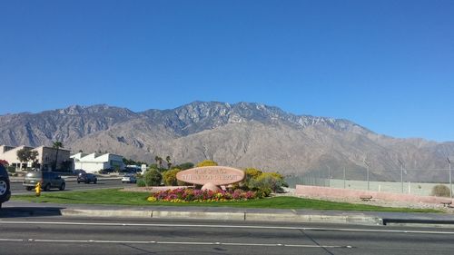 Road leading towards mountains against blue sky