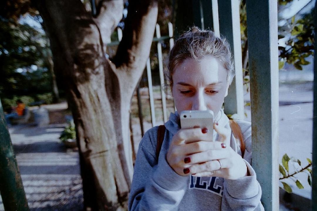 MIDSECTION OF YOUNG WOMAN USING MOBILE PHONE AT CAMERA