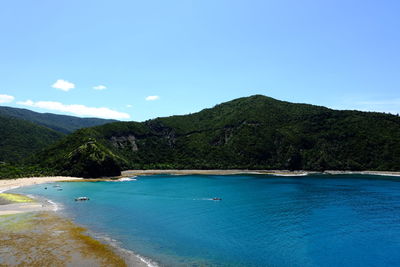 Scenic view of sea and mountains against blue sky