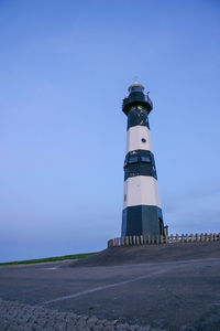 Lighthouse by sea against clear sky