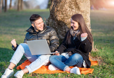 Young woman using laptop while sitting on field