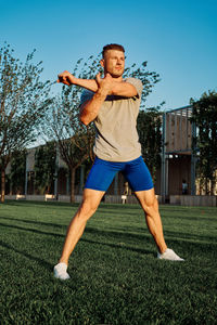 Full length of young woman exercising on field