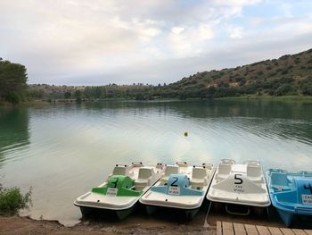 Boats moored on lake against sky