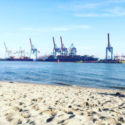 Cranes at commercial dock against blue sky