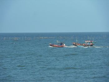Boats sailing in sea against clear sky