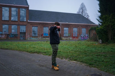 Rear view of man walking on footpath against building