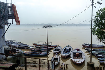 Boats moored in calm sea against clear sky